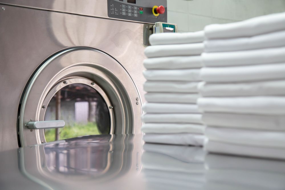 Stack,Of,Clean,Bed,Sheets,In,Front,Of,Industrial,Washing Stack,Of,Clean,Bed,Sheets,In,Front,Of,Industrial,Washing